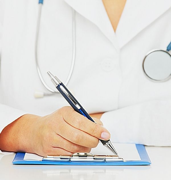 Arzt schreibt mit dem Kugelschreiber auf ein weißes Blatt Papier auf einem blauen Klemmbrett