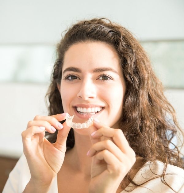 Lächelnde Frau setzt sich eine transparente Zahnschiene ein