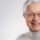 Ältere Frau mit grauen Haaren und Brille lächelt